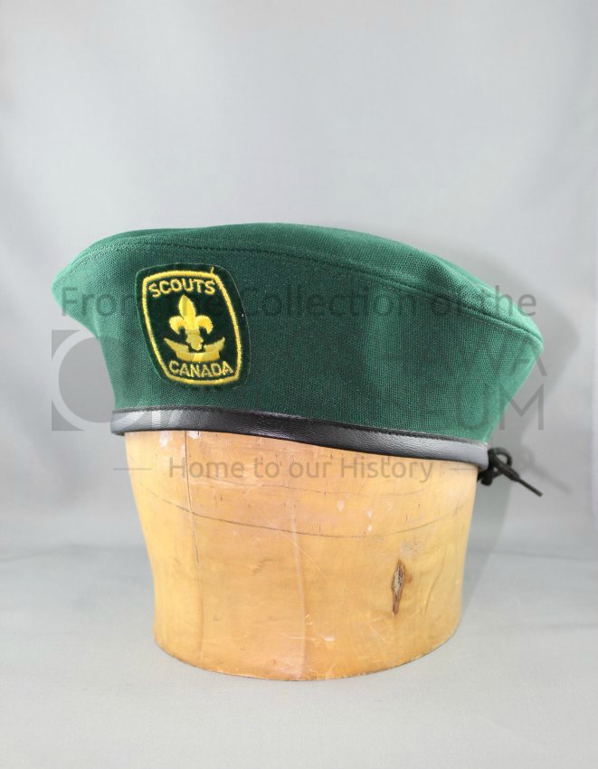 Green Scouts Canada beret on a wooden hat block