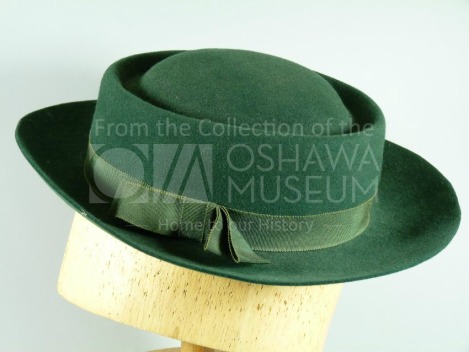 Green brimmed hat on a wooden hat block