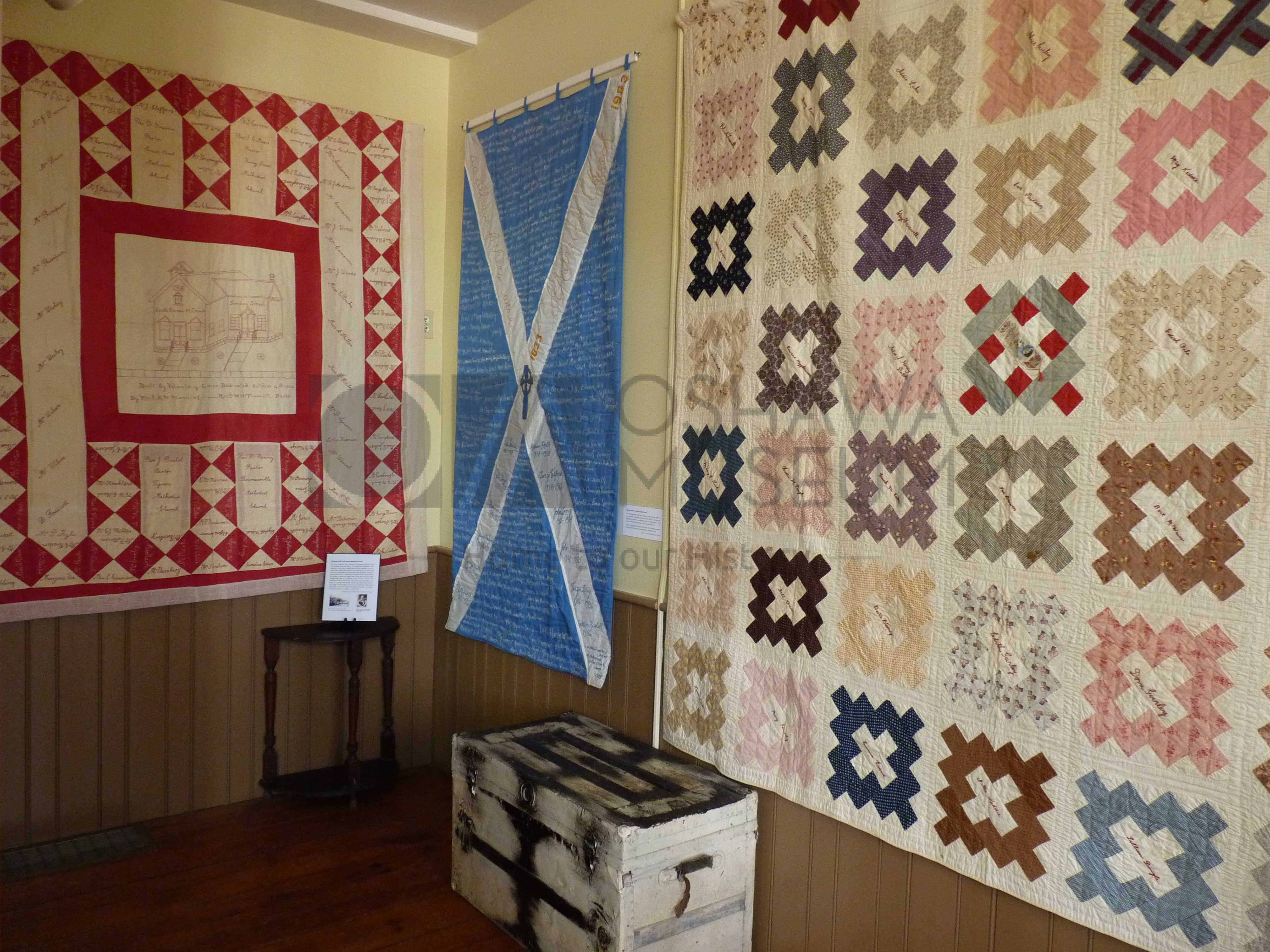 A room with colourful quilts handing on the walls